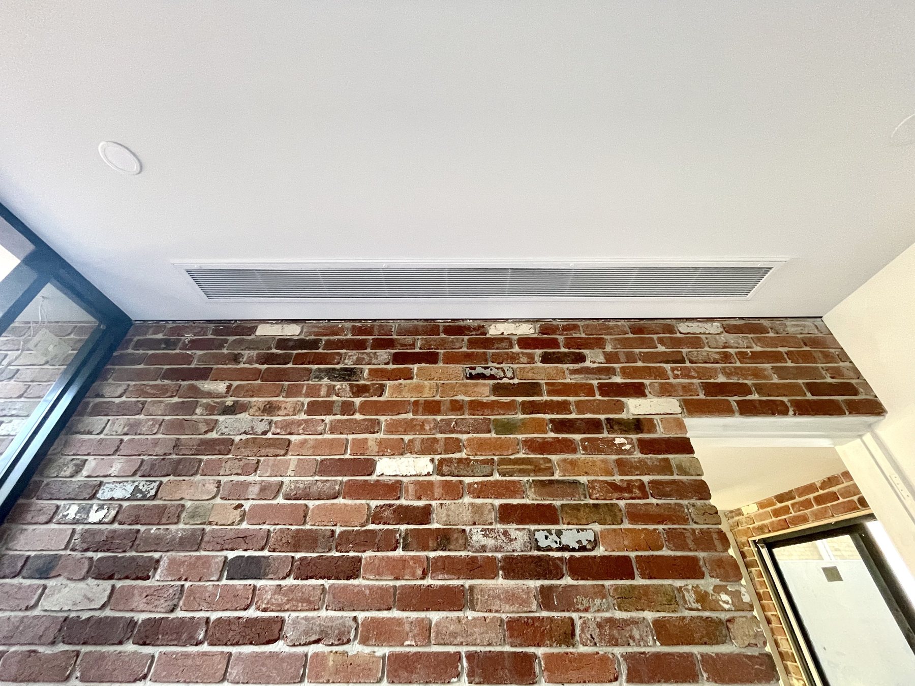 Linear ceiling outlet above a brick feature wall